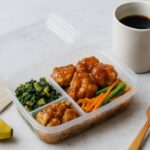 冷蔵宅配食の盛り付け例。葉物野菜、鶏肉、人参とインゲンの副菜が整然と詰められたプラスチック容器。